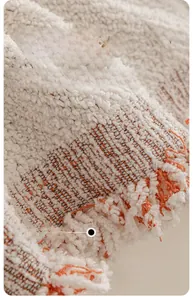 Gros plan sur la housse de canapé en chenille avec glands orange et texture tissée