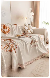 Détail de la housse de canapé en chenille avec motif floral orange, franges et texture