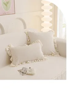 Gros plan du coussin à volants crème et housse de canapé texturée avec détails dentelle