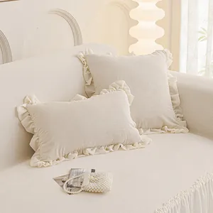 Coussins décoratifs blanc crème à volants et texture côtelée sur un canapé en tissu