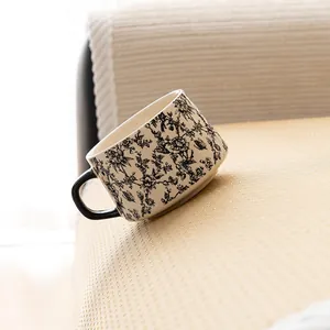 Elegant Toile de Jouy ceramic mug with black floral pattern on textured beige fabric