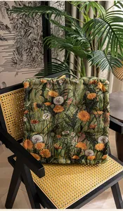 Detail van een vierkant dik kussen met oranje bloemenjacquard en handvat opzij