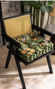 Detail van dik bloemen jacquard stoelkussen op een vintage rotan stoel met houten frame
