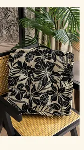 Detail van zwart bloemen zitkussen met handvat op vintage rieten stoel