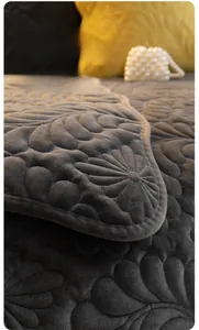 Detail of dark grey plush sofa cover showing floral quilted texture and soft fabric