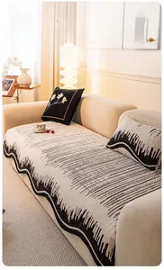 Detail of cream-colored knitted sofa cushion with black wave patterns and textured finish