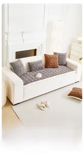 Close-up of thick plush sofa cushion with 3D geometric texture and pom-pom lace edge