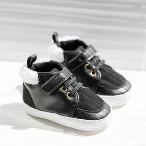 Minimalist black warm baby boots with faux leather and fleece lining on white background