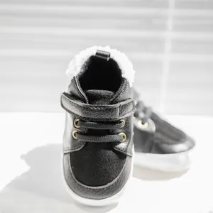 Detail of black baby winter shoes with white fleece lining and Velcro strap closure