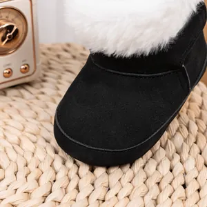 Gros plan sur des bottes d'hiver bébé noires avec fourrure blanche et texture en daim