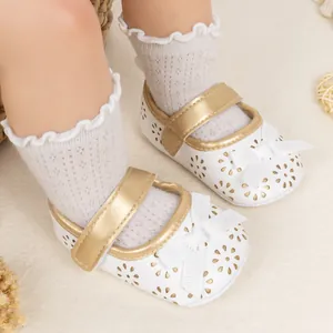Detail of baby princess shoes with gold straps, white bows, and floral cutouts
