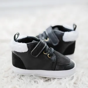 Detail of baby winter boots with black leather, white faux fur lining and velcro strap