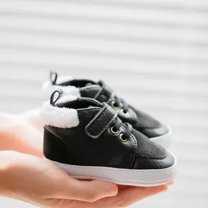 Detailed view of black infant winter shoes featuring soft faux fur lining and velcro strap