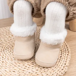 Gros plan de bottines bébé d'hiver avec col en fourrure et daim sur tapis tissé
