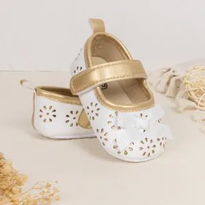 Detailed view of floral laser-cut baby princess shoes with white ribbon bow and velcro strap
