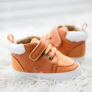 Detailed close-up of brown baby winter shoes with white faux fur lining and velcro strap