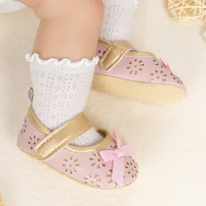 Detailed close-up of pink baby princess shoes featuring gold straps and ribbon bow