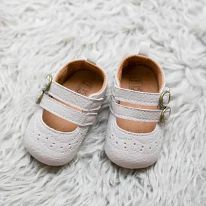 Κάτοψη από κρεμ παπούτσια Mary Jane για μωρά με brogue λεπτομέρειες σε βελούδινο φόντο