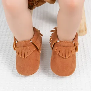 Gros plan de mocassins pour bébé en daim marron avec des détails de franges doubles