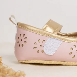 Detail of pink baby girl shoes with hollow floral pattern and gold metallic trim edges