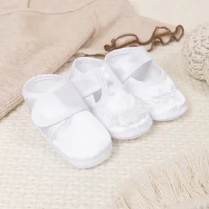 Détails de chaussures de baptême en satin blanc avec dentelle et motifs brodés