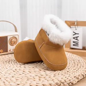 Bottes d'hiver bébé en daim camel avec doublure en fausse fourrure sur tapis rustique