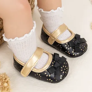Detailed view of baby Mary Jane shoes with hollow floral patterns and gold bow strap