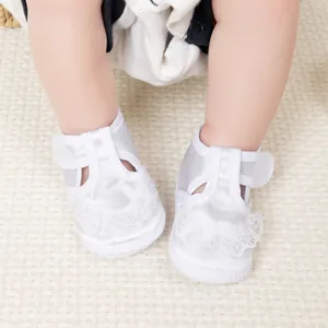 Détail de chaussures de baptême en satin blanc avec dentelle et velcro