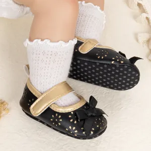 Close-up of baby princess shoes with black bow, gold straps, and non-slip dotted soles