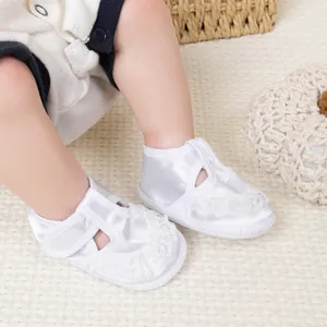 Détail de chaussures de baptême pour bébé en satin blanc avec dentelle et brides