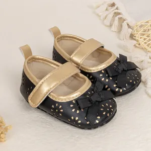 Detail of baby Mary Jane shoes with black PU leather, gold trim, and bow decoration