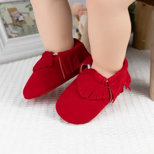 Gros plan de mocassins pour bébé en daim rouge avec franges et bordure élastique