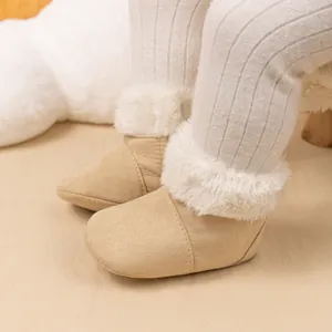 Close-up of beige baby winter boots with warm faux fur trim and soft suede texture