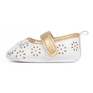 Detailed side view of white PU baby Mary Janes with gold trim and hollow floral patterns