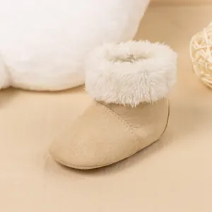 Detail of warm baby winter boots with soft beige faux suede and fluffy faux fur trim