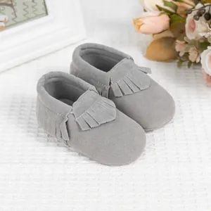 Gros plan détaillé de mocassins pour bébés en daim gris avec d'élégantes franges