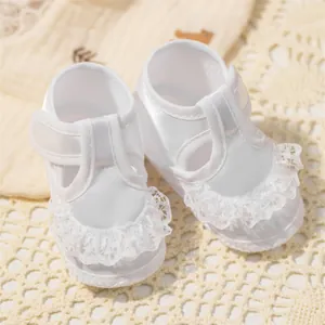 Vue détaillée de chaussures de baptême blanches avec dentelle et finition satinée