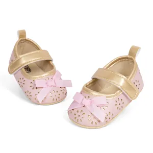 Detail view of pink baby Mary Jane shoes with gold velcro strap and hollow flower pattern