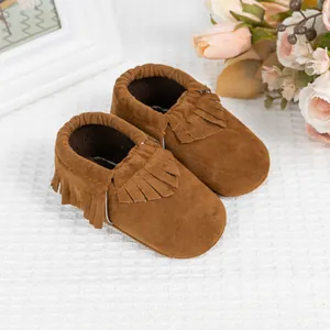 Gros plan de mocassins pour bébé en daim marron avec détails à franges et élastique