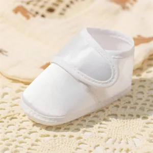 Détail de chaussures bébé en satin blanc avec scratch sur un tapis en crochet doux