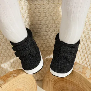 Close-up of baby boy sneakers with velcro straps and soft soles on cream knit background
