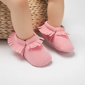 Gros plan de bottines roses pour bébé à franges avec semelles souples et effet daim