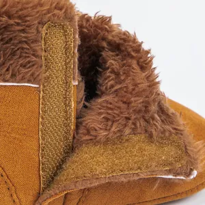 Detailed close-up of brown baby boots showing soft fleece lining and velcro strap closure
