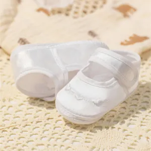 Détails de chaussures bébé en satin blanc avec broderie en V et fermeture velcro baptême