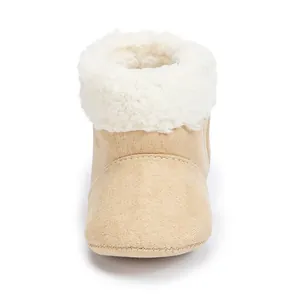 Close-up of warm beige baby boots with soft fabric and white faux fur trim detail