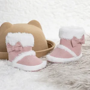 Pink soft sole baby boots with bows and faux fur lining for infants on plush rug
