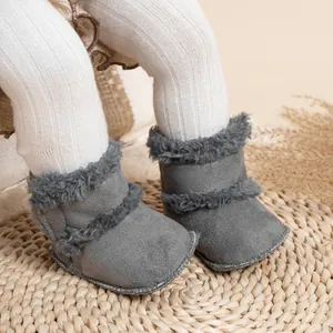 Détail de bottines d'hiver grises pour bébé avec fourrure sur un tapis tressé doux