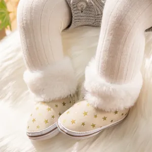 Close-up of baby snow boots with gold star print and white faux fur trim on soft carpet