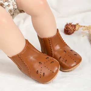 Close-up of brown leather baby boots with laser-cut floral patterns and non-slip rubber sole