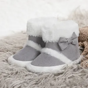 Detail of baby girl fleece boots with soft soles and grey bows on a textured carpet